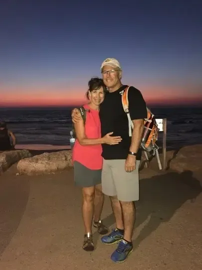 A man and woman standing on the beach at sunset.