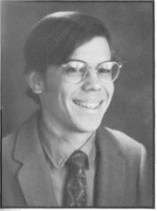 A young man wearing glasses and smiling.