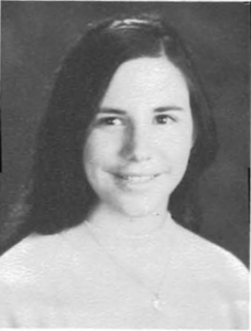 A young woman smiling for the camera in an old photo.