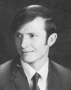 A man in suit and tie smiling for the camera.