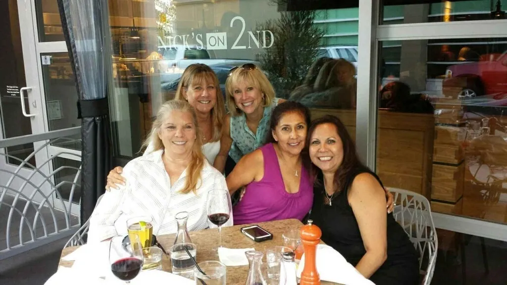 A group of women sitting at a table with wine glasses.